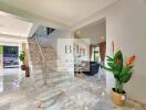 Spacious main living area with marble floors, staircase, and indoor plants