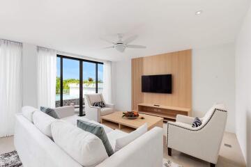 Modern living room with white sofas, TV, and large window