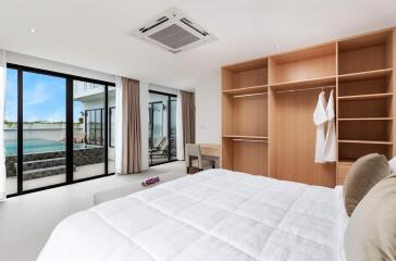 Modern bedroom with large windows, pool view, and built-in wooden wardrobe