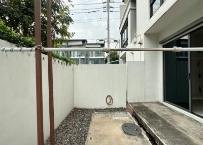 Outdoor area of a property with concrete flooring, a white wall, and an exterior pipe