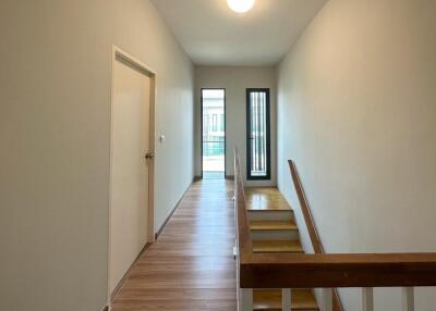 Bright hallway with wooden flooring and a door leading outside