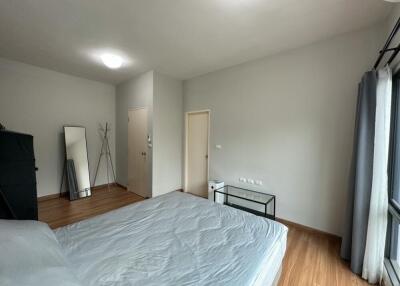 Bedroom with a double bed, wooden flooring, and a large window with curtains