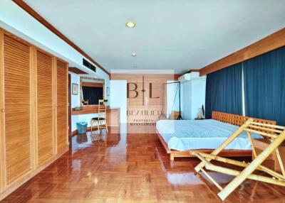 Spacious bedroom with wooden flooring, large wardrobe, and ample natural light