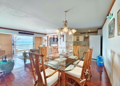 Open living and dining area with glass dining table, wicker chairs, and a view of the waterfront