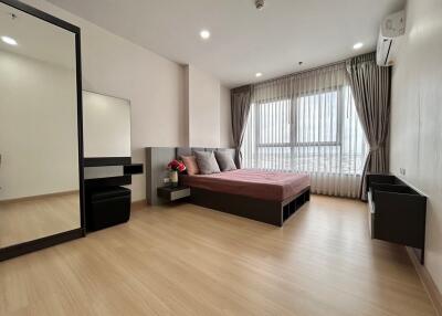 Modern bedroom with wooden flooring, large window, and contemporary furnishings