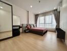 Modern bedroom with wooden flooring, large window, and contemporary furnishings