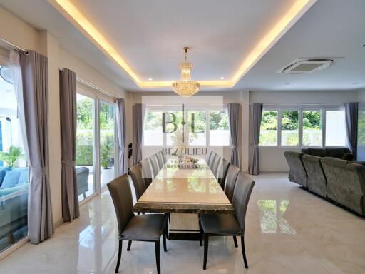 Modern dining room with large table, chandelier, and natural lighting