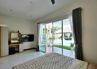 Spacious bedroom with sliding glass doors opening to a pool view