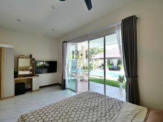 Spacious bedroom with sliding glass doors opening to a pool view