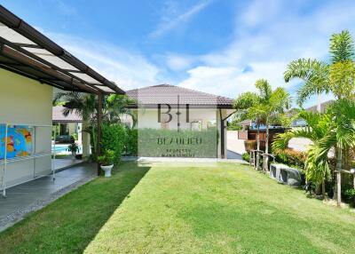 Beautiful backyard with lush green lawn, palm trees, and outdoor structures