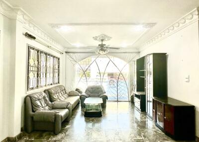 Spacious and well-lit living room with sofas, a coffee table, and large windows.