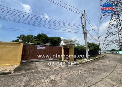 Gated entrance of a property with surrounding trees and power lines