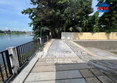 Pathway with trees, river view, and boundary wall