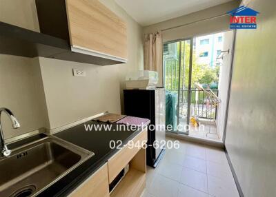 Small kitchen area with sink, countertop, and balcony view.