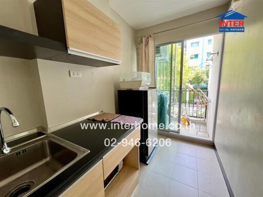 Small kitchen area with sink, countertop, and balcony view.