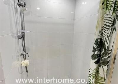 Modern tiled shower area with a tropical-themed shower curtain