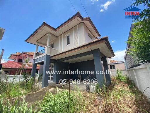 Two-storey detached house with surrounding vegetation and a paved driveway.