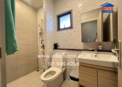 Modern bathroom with toilet, sink, mirror, and shower area