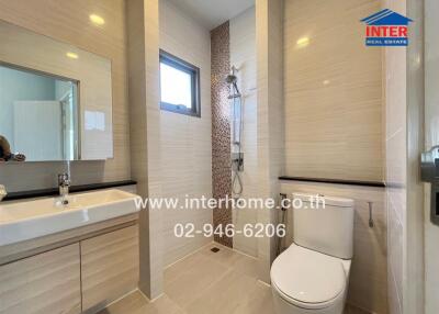 Modern bathroom with white fixtures and beige tiles.