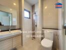 Modern bathroom with white fixtures and beige tiles.