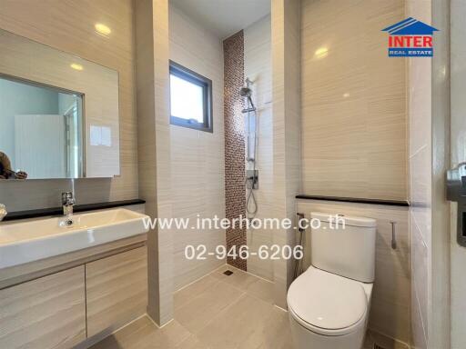 Modern bathroom with white fixtures and beige tiles.