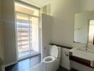 Modern bathroom with toilet, sink, and large window