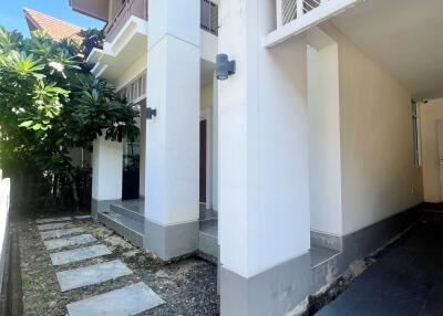 Exterior view of a modern residential building with a walkway and lush greenery