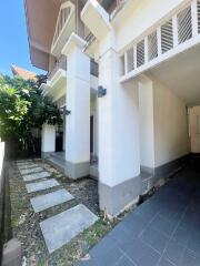 Exterior view of a modern residential building with a walkway and lush greenery