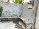 Outdoor area with concrete bench and wall, outdoor light fixture, trampoline, and greenery