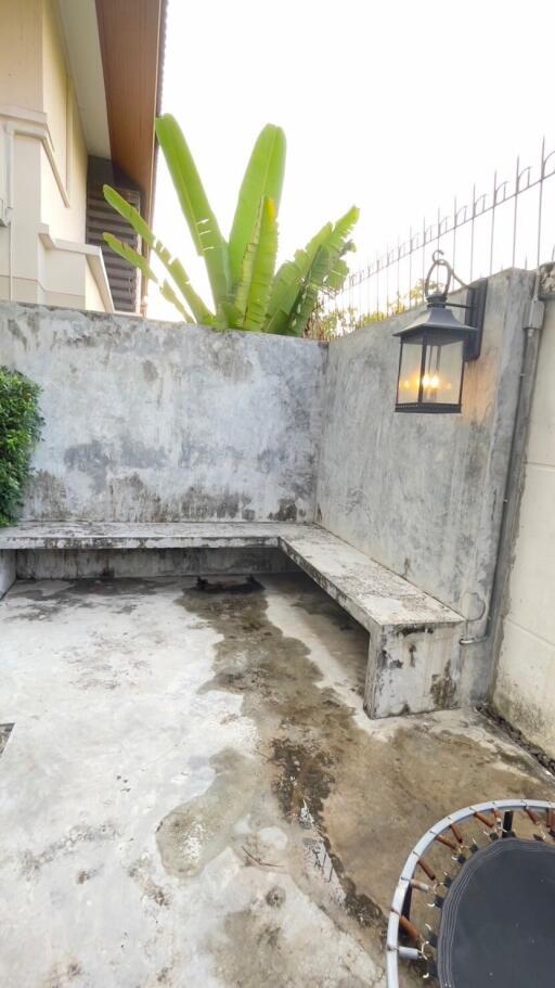 Outdoor area with concrete bench and wall, outdoor light fixture, trampoline, and greenery