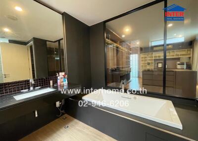 Modern bathroom with bathtub, large mirror, and sink.