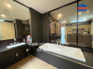 Modern bathroom with bathtub, large mirror, and sink.