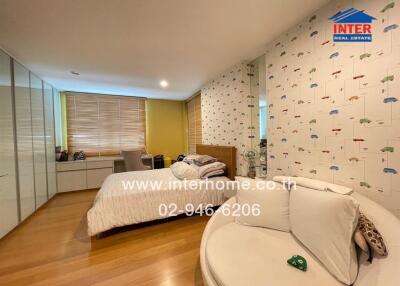 Spacious bedroom with large window, wooden flooring, and a comfortable seating area