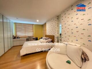 Spacious bedroom with large window, wooden flooring, and a comfortable seating area