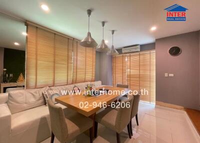 Modern dining area with wooden table, white sofa, and pendant lights