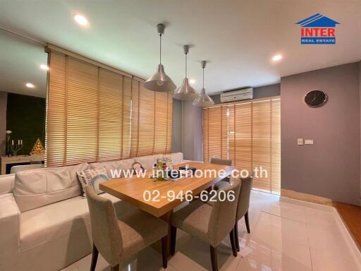 Modern dining area with wooden table, white sofa, and pendant lights