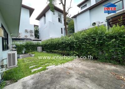 Backyard with grass, plants, and neighboring buildings