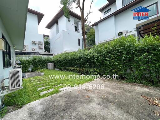 Backyard with grass, plants, and neighboring buildings