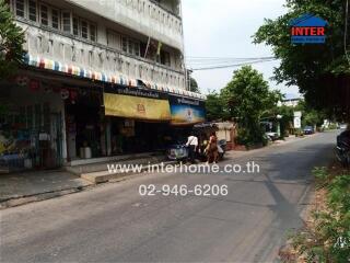 Street view of a building with shops and a sidewalk