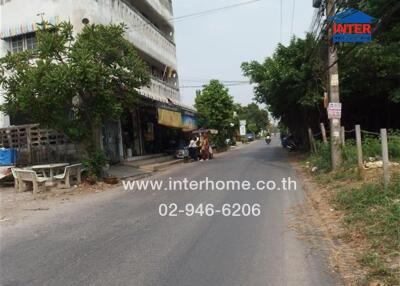 Street view of a building with nearby shops and trees