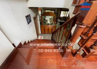 Wooden staircase leading to lower floor with decorative items and contact information