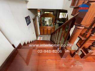 Wooden staircase leading to lower floor with decorative items and contact information