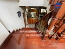 Wooden staircase leading to lower floor with decorative items and contact information