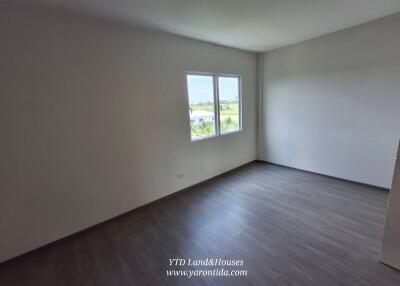 Empty bedroom with large windows and wooden flooring