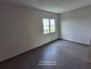 Empty bedroom with large windows and wooden flooring