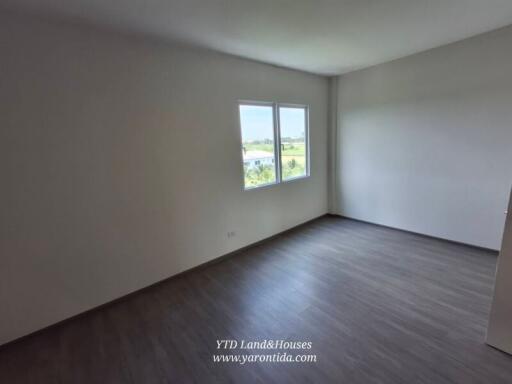 Empty bedroom with large windows and wooden flooring