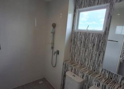 Modern bathroom with shower, toilet, sink, and window