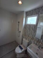 Modern bathroom with shower, toilet, sink, and window