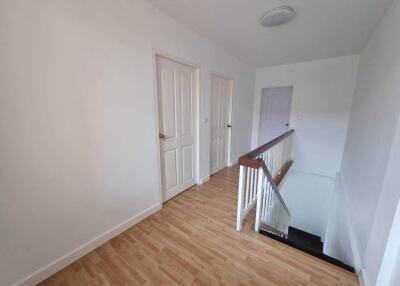 Well-lit hallway with wooden flooring and multiple doors