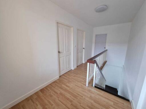 Well-lit hallway with wooden flooring and multiple doors